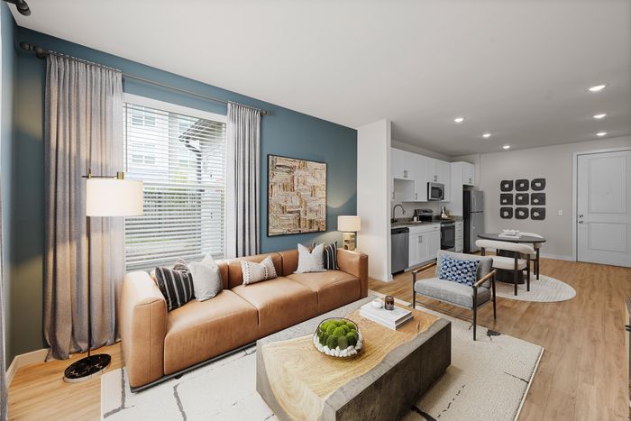 Chic open-plan living space featuring a cozy leather sofa, modern kitchen, and elegant dining area with abundant natural light.
