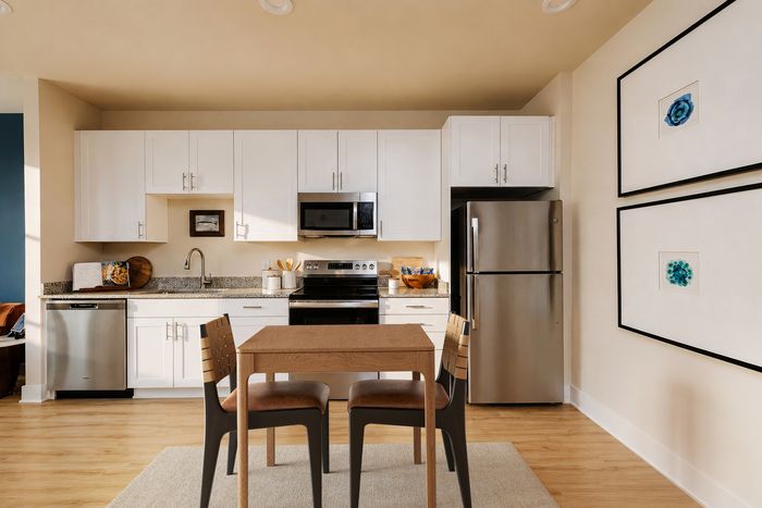 Modern kitchen with sleek white cabinets, stainless steel appliances, and a cozy dining area for two.