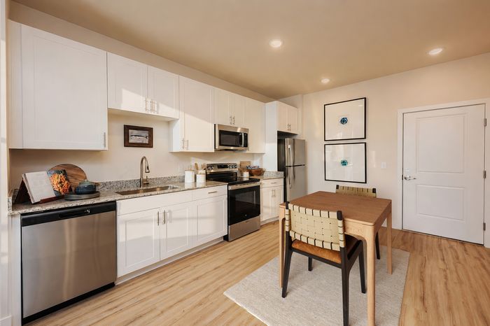 Chic kitchen featuring sleek white cabinetry, stainless steel appliances, and a cozy dining area for modern living.