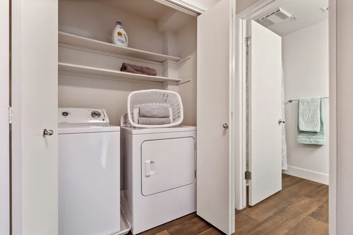 Modern laundry nook with washer, dryer, and stylish shelving in a bright, organized space.