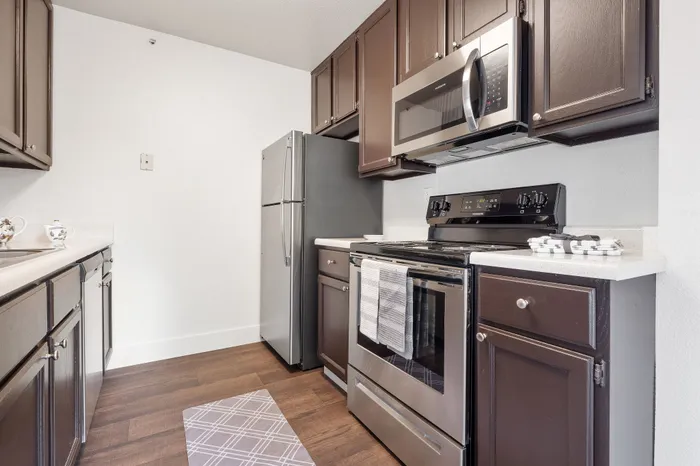 Modern kitchen with sleek dark cabinets, stainless steel appliances, and elegant white countertops.