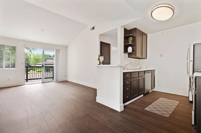 Bright, airy apartment with hardwood floors, modern kitchen, and balcony with lush views.