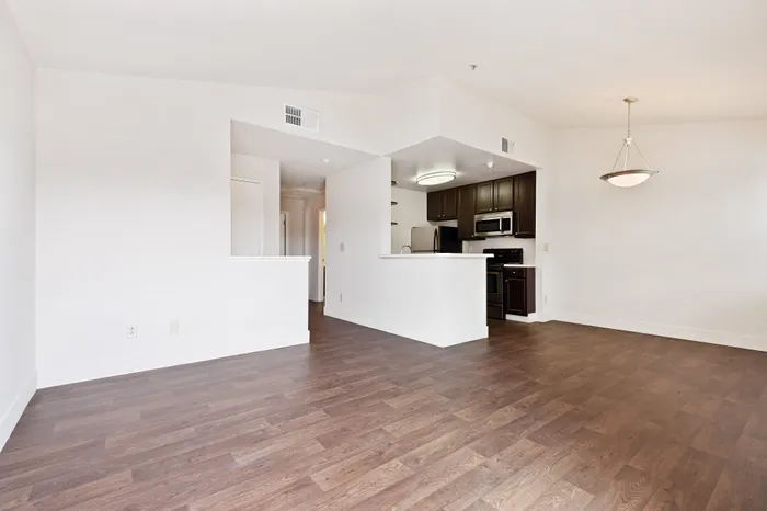 Contemporary open-plan kitchen and living area with elegant dark wood flooring and modern fixtures.