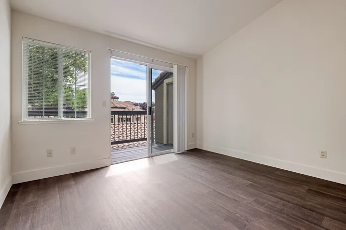 Bright and airy apartment bedroom with modern flooring, large windows, and patio access offering stunning views.
