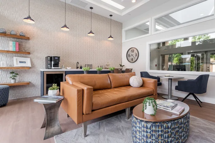 Modern living area featuring a stylish leather sofa, elegant wall decor, and a cozy coffee nook with lush greenery accents.