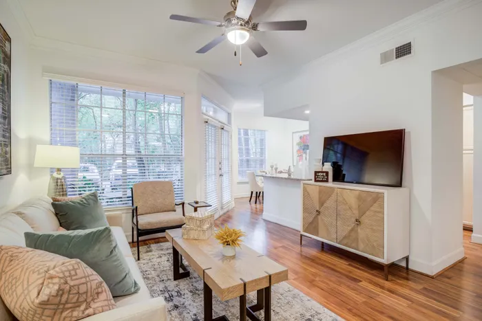 Modern living room with elegant hardwood floors, cozy sofa, large windows, and stylish decor.