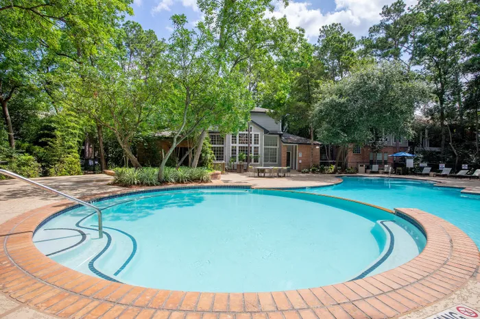 Inviting communal swimming pool surrounded by lush greenery and modern patio seating, perfect for relaxation and leisure.