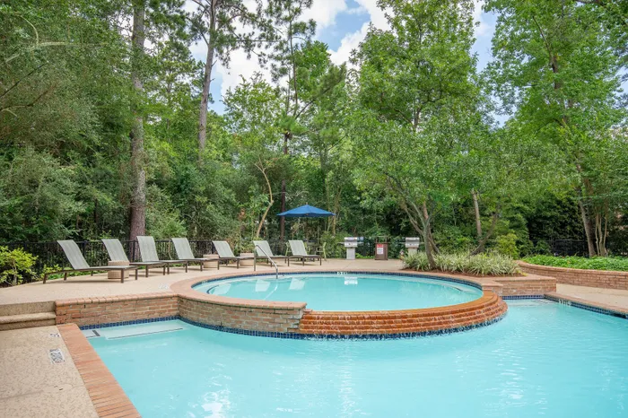 Serene outdoor pool surrounded by lush greenery and comfortable lounge chairs, perfect for relaxation.