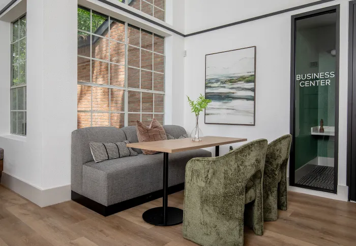 Chic interior with modern seating arrangement next to a glass-walled business center, featuring elegant decor and a vibrant green plant for a refreshing ambiance.