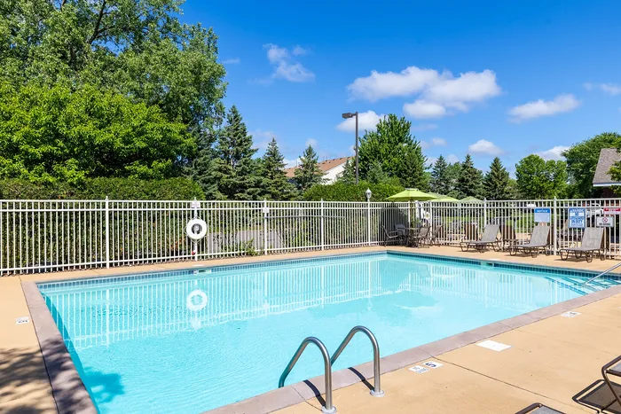 Inviting outdoor pool area with crystal-clear water, surrounded by lush greenery and comfortable lounge chairs, perfect for relaxation and leisure.