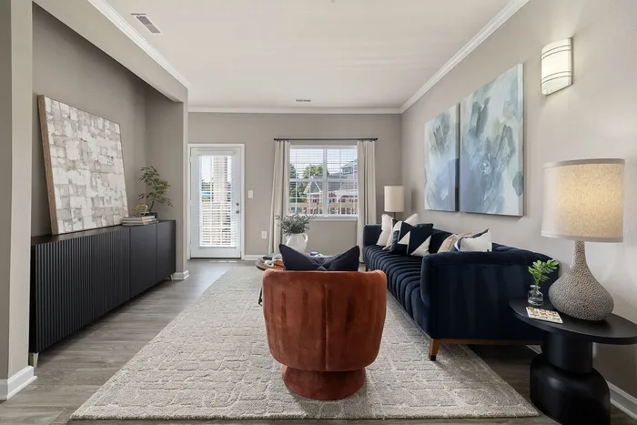 Elegant living room featuring a plush navy blue sofa, chic abstract art, and modern lighting, creating a warm and inviting atmosphere.