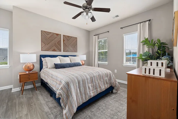 Bright and inviting bedroom with modern decor, featuring a cozy bed, elegant wooden furniture, and large windows offering natural light.