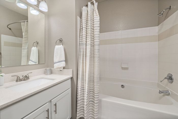 Elegant bathroom with a modern design featuring a pristine bathtub, sleek vanity, and stylish lighting.
