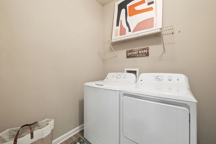 Chic laundry room with modern washer and dryer, stylish art, and practical shelving.