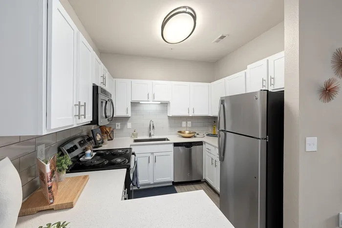 Modern kitchen with sleek stainless steel appliances, white cabinetry, and a stylish countertop, creating a bright and welcoming space.