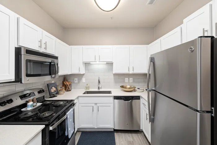 Modern kitchen with sleek stainless steel appliances, white cabinetry, and elegant subway tile backsplash.