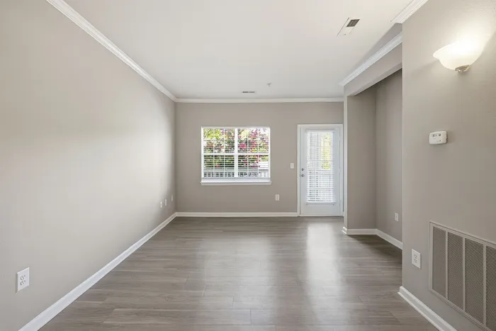 Bright and inviting living room with modern wood flooring, neutral walls, and ample natural light from large windows.