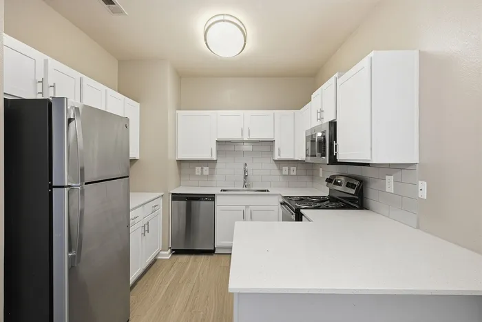Modern kitchen with sleek stainless steel appliances, pristine white cabinetry, and stylish backsplash.
