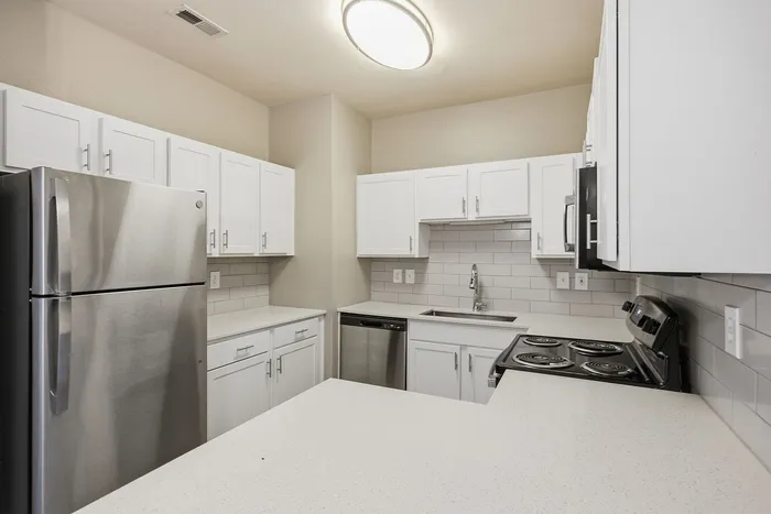 Modern kitchen with sleek stainless steel appliances, glossy white cabinetry, and a stylish tiled backsplash.