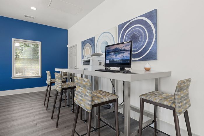 Modern communal workspace with high-top seating, vibrant blue accent wall, and computer setup.