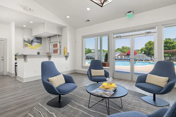 Contemporary lounge area with plush blue chairs, modern art, and pool views through large windows, perfect for relaxation and leisure.