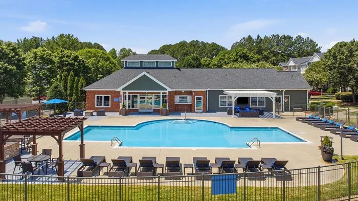 Elegant residential complex featuring a sparkling outdoor pool, surrounded by stylish lounge chairs and vibrant greenery, perfect for relaxation.
