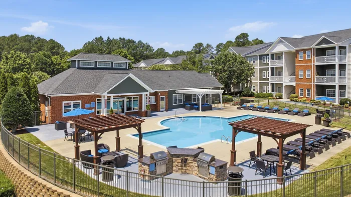 Luxury apartment complex with a modern swimming pool, surrounded by elegant sun loungers and inviting pergolas, offering a premium outdoor living space.