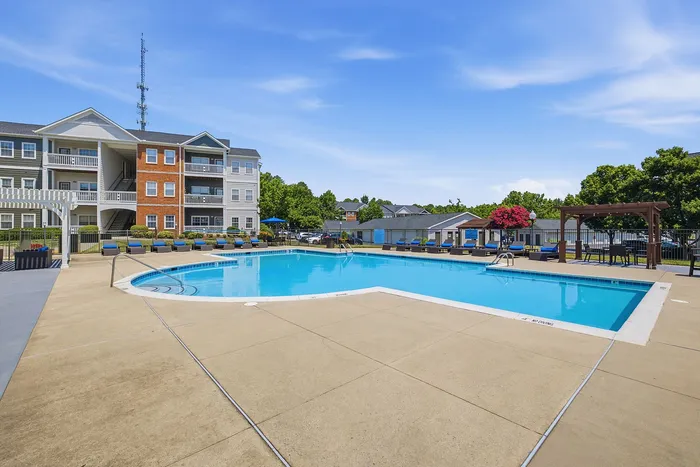 Inviting apartment complex featuring a pristine pool, surrounded by comfortable lounge chairs and lush greenery.