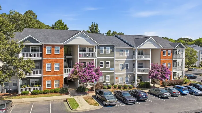 Charming apartment complex with brick and siding exterior, featuring private balconies and beautiful landscaping.