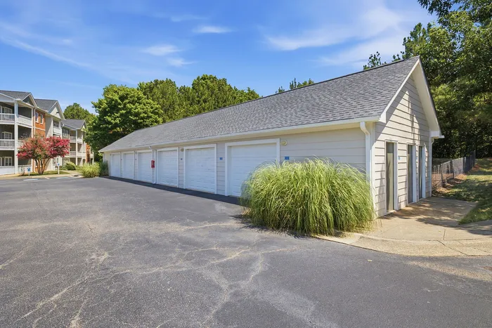 Charming apartment complex with modern garages and lush greenery under a clear blue sky.