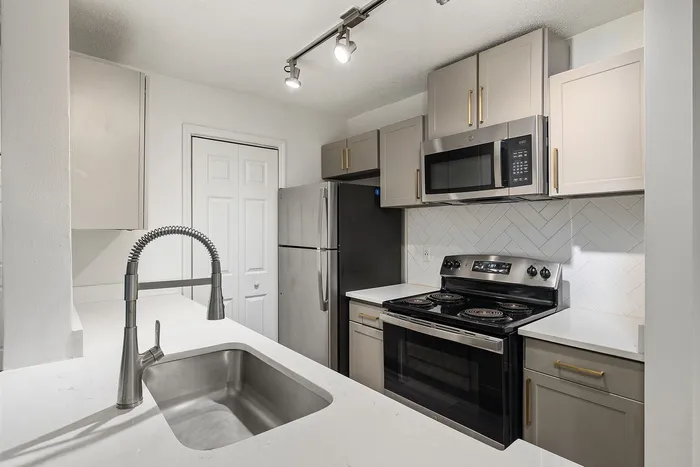Modern kitchen with sleek stainless steel appliances, elegant tile backsplash, and stylish cabinetry.