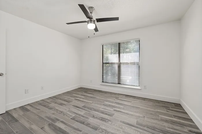 Bright and modern room featuring sleek wood-look flooring and a stylish ceiling fan, ideal for creating a comfortable living space.