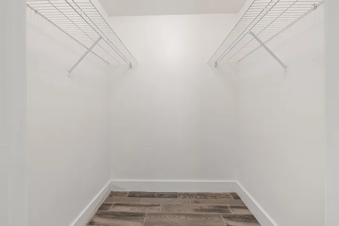 Spacious walk-in closet with elegant hardwood flooring and ample shelving, perfect for stylish storage solutions.
