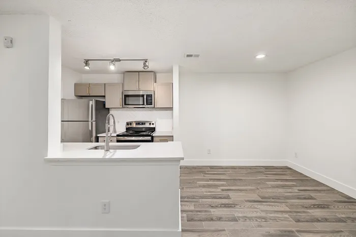 Modern kitchen with sleek stainless steel appliances, stylish cabinetry, and warm wood flooring, perfect for contemporary living.
