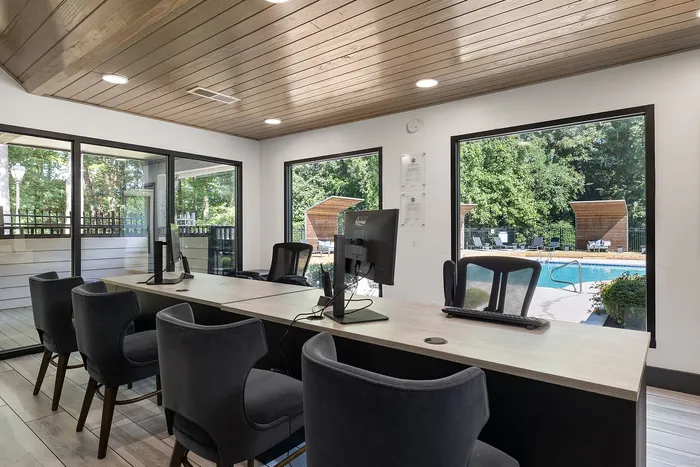 Modern office space with sleek black chairs overlooking a serene outdoor pool area through large windows, offering an inspiring work environment.