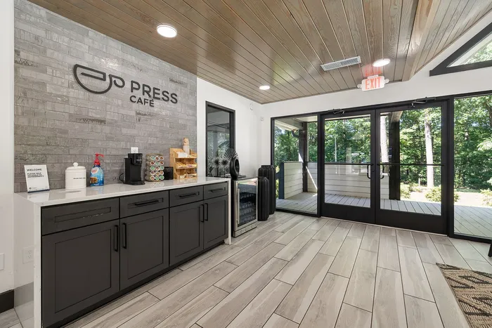 Chic cafe with modern design featuring stylish countertops, sleek cabinets, and a serene view through large glass doors.