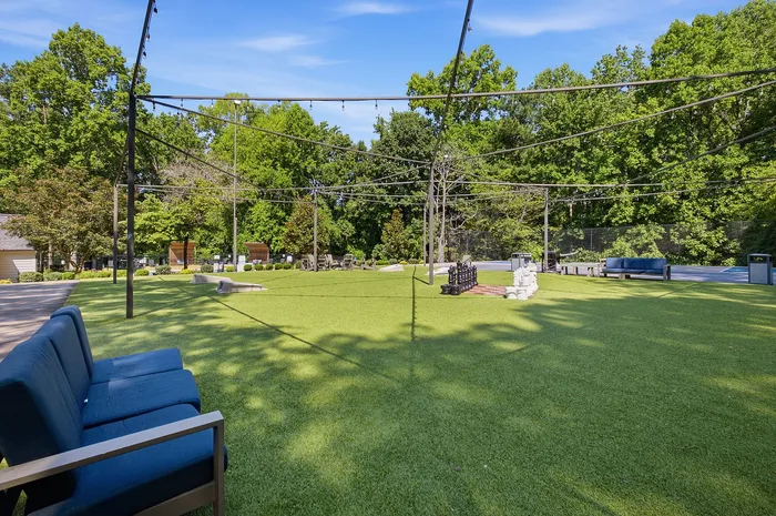 Inviting outdoor space with lush greenery, comfortable seating, and decorative string lights ideal for relaxation and social gatherings.