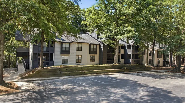 Charming apartment complex nestled among lush trees, featuring multiple units with ample natural light and modern design.