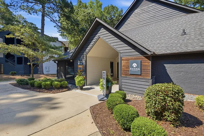 Inviting entrance to a contemporary apartment complex surrounded by lush landscaping and modern architecture.