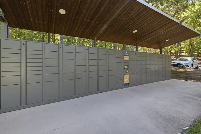 Modern outdoor package locker system under a stylish wooden canopy, enhancing convenience with 24/7 access amid scenic greenery.