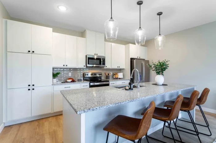 Modern kitchen with sleek white cabinets, granite countertops, and contemporary lighting over a breakfast bar with stylish seating.