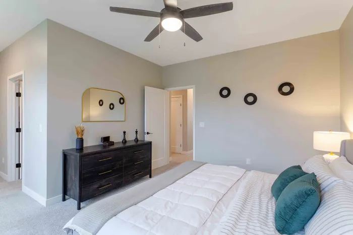 Elegant bedroom featuring a cozy bed with plush pillows, a sleek dresser with decorative accents, and soft neutral tones complemented by modern lighting.