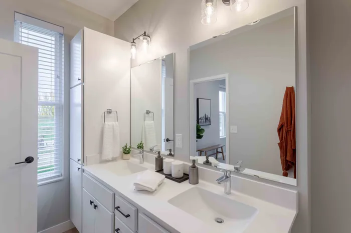 Contemporary bathroom with dual sinks, elegant lighting, and a large mirror enhancing the space.