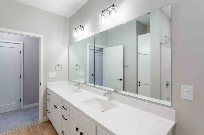 Elegant modern bathroom with double sinks, large mirror, and ambient lighting.
