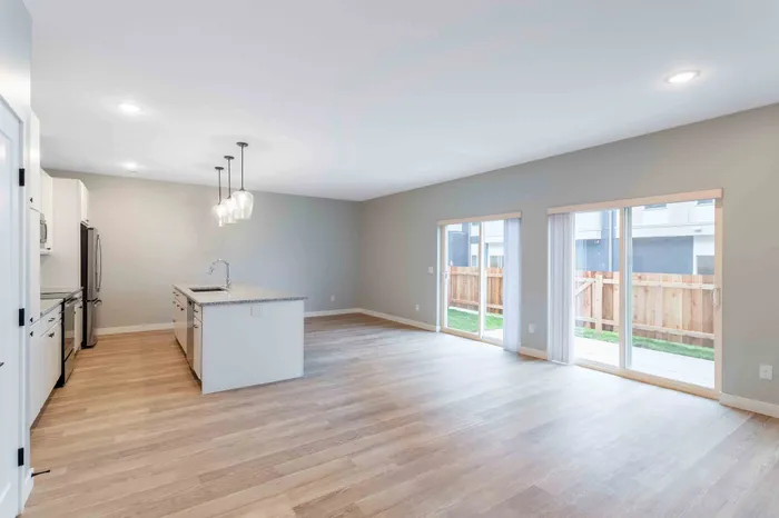 Bright and airy kitchen with granite island, modern fixtures, and expansive sliding glass doors leading to a private patio.