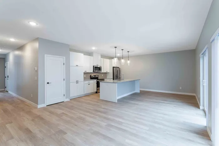Modern open-concept kitchen with sleek cabinetry, stainless steel appliances, and elegant pendant lighting over a spacious island, perfect for entertaining.