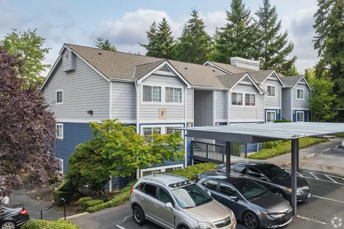 Charming two-story apartment complex with modern architecture, surrounded by lush greenery and ample parking spaces.