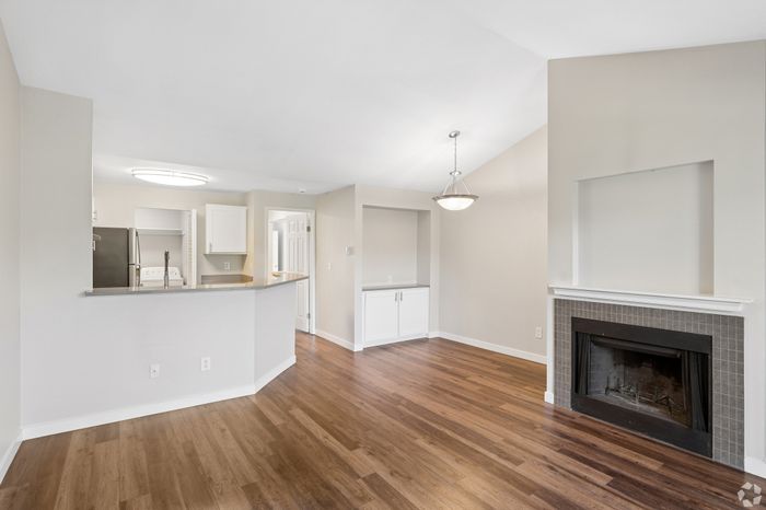 Bright and airy open living space with elegant hardwood floors, sleek modern kitchen, and a cozy fireplace for ultimate comfort.
