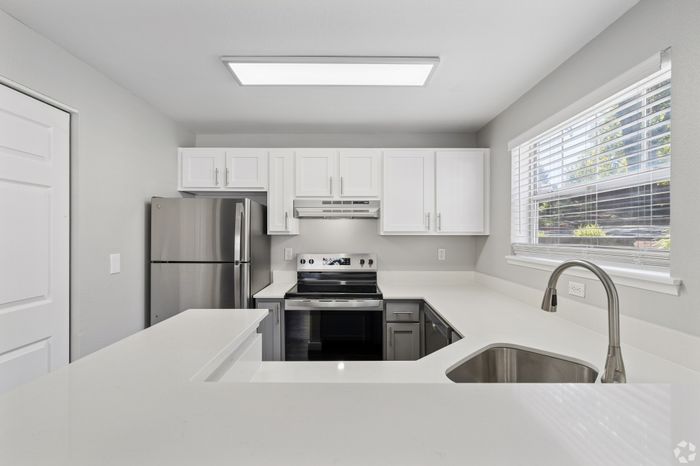 Modern kitchen with sleek stainless steel appliances, white cabinetry, and a large window for natural light.