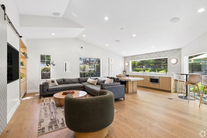 Bright and modern living space with an open-concept layout, featuring a cozy sectional, stylish kitchen, and ample natural light through large windows.